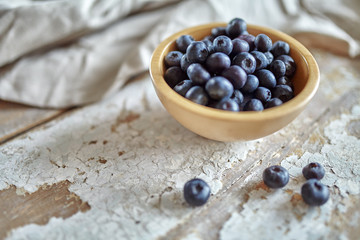 Image of blueberries in wooden bowl on rustic village table.