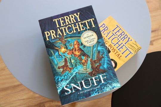 WARSAW, POLAND - APRIL 21, 2020: Two Discworld series fantasy books by British author Terry Pratchett on a coffee table.