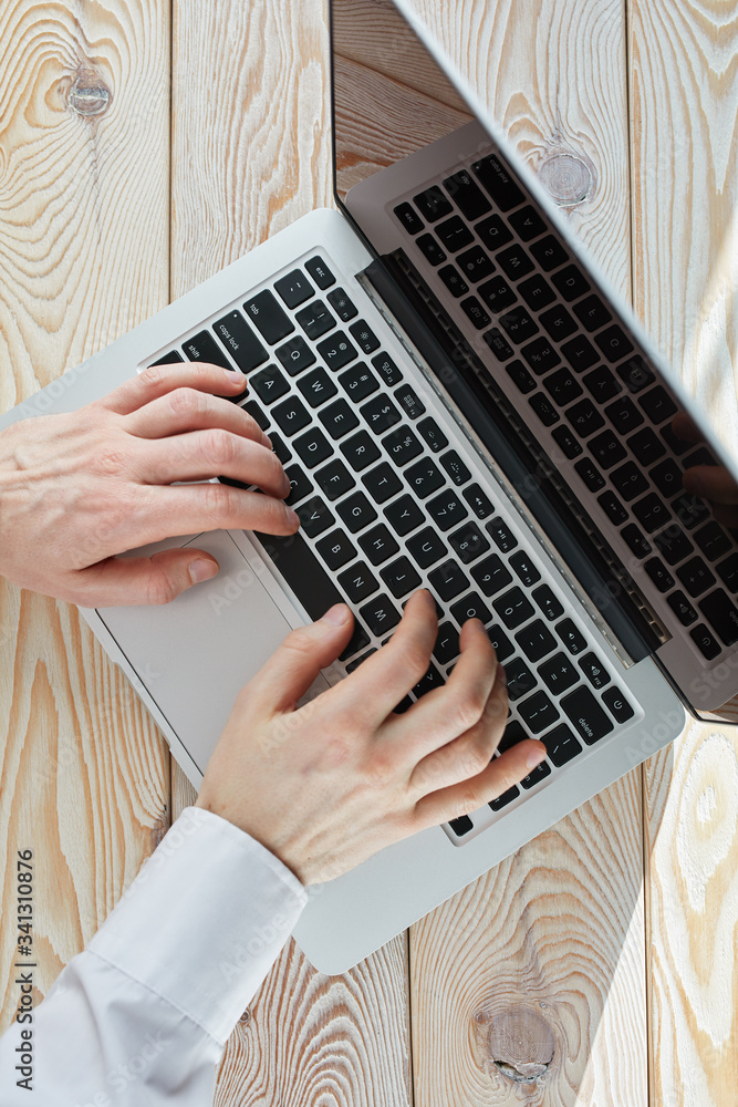 Poster top view of man's hands typing on laptop in sunny day. coworking or working at home concept image.