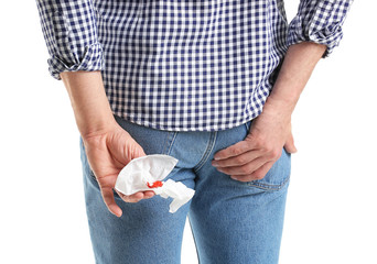 Young man holding toilet paper with blood spot on white background. Hemorrhoids concept