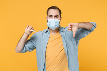 Young man in sterile face mask posing isolated on yellow wall background studio portrait. Epidemic...