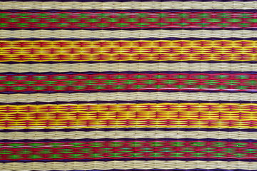 Reed mats, close up texture of native thai style weave sedge mat color Yellow alternating red and...