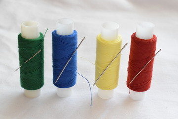 A set of sewing threads, needles, pins.