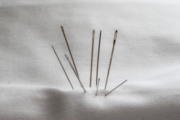 A set of sewing threads, needles, pins.