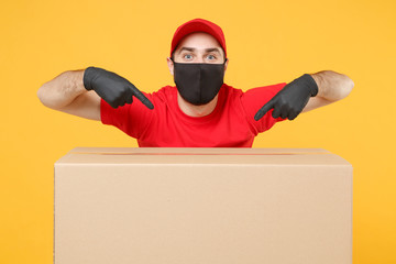 Delivery man employee in red cap blank t-shirt uniform face mask glove hold empty cardboard box isolated on yellow background studio Service quarantine pandemic coronavirus flu virus 2019-ncov concept