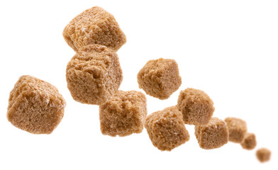 Brown cane sugar levitates on a white background