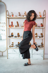 portrait of beautiful asian woman try to put a shoes on while shopping in fashion boutique store. fitting customer