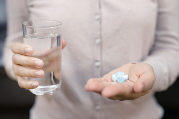 close up hand woman taking pill take a medicine in hand holding a cup glass of drinking water. Stop drug use Taking Medication health care medical concept.