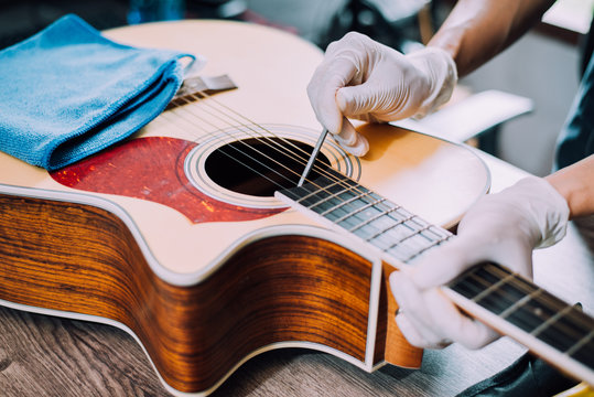 Acoustic guitar repairman, Screw the guitar neck, Close-up.