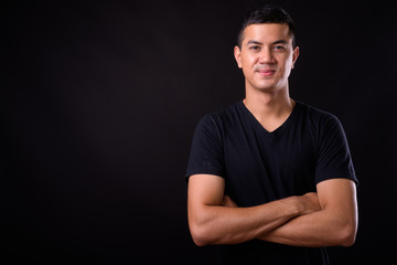 Portrait of young handsome Asian man with arms crossed