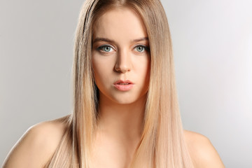 Fototapeta premium Young blonde with beautiful hair on grey background