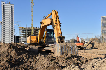 Excavators during earthmoving at construction site. Backhoe dig ground for the construction of foundation and laying sewer pipes district heating. Earth-moving heavy equipment on road works