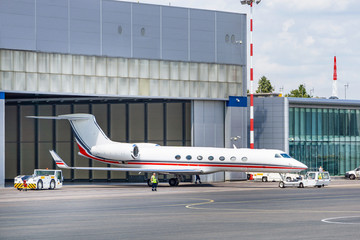 Business jet is being towed from the hangar by pushback tug