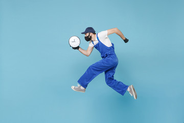 Fun jumping delivery man in cap t-shirt uniform sterile face mask glove isolated on blue background...