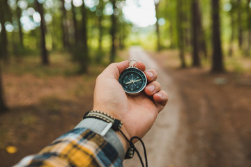 compass in man hand hiking by forest trail