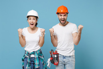 Overjoyed couple woman man in casual clothes protective helmet hardhat isolated on blue background....