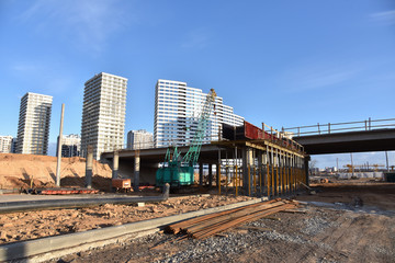 Fototapeta premium Roundabout and traffic bridge construction. Construction highway ramps and bridgeworks. Crane for formwork on bridge project works. Road work on traffic highway, road intersection junction and freeway