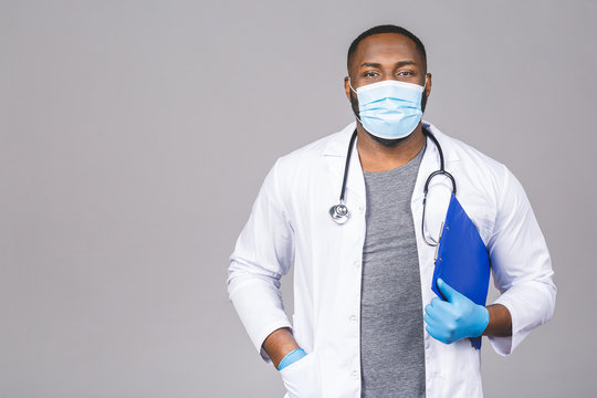 African american doctor man in face mask gloves isolated on grey background. Epidemic pandemic coronavirus 2019-ncov sars covid-19 flu virus. Holding clipboard.