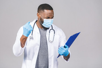 African american doctor man in medical gown face mask gloves isolated on grey background. Epidemic...