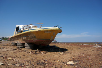 Old abandoned wrecked speed boat at ship or boat graveyard. Lots of different dry docked.   