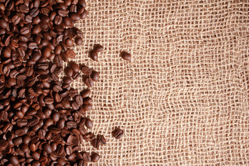 Dark roasted coffee beans on burlap sack. Closeup, copy space, top view. Agriculture, coffee shop  concept