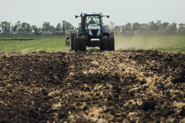 Obraz premium big blue tractor with big wheels in a field in summer at an agricultural exhibition