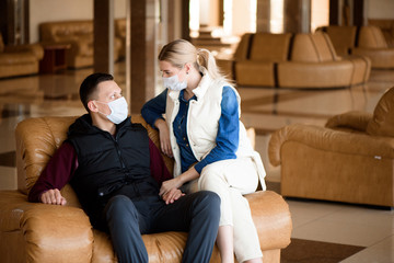 Young couple wearing a mask in an airport lounge. Coronavirus influenza virus travel concept.