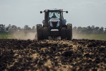 Fototapeta premium big blue tractor with big wheels in a field in summer at an agricultural exhibition