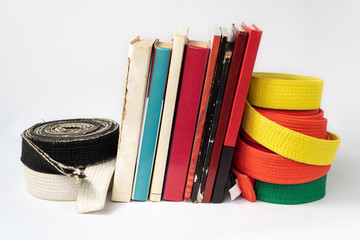 Black and white martial arts belt on a stack of books on the study of martial arts of aikido,...