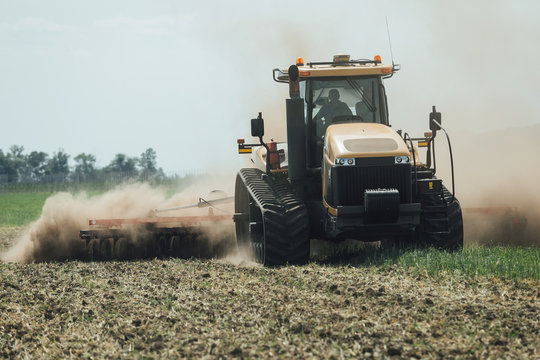 Yellow Caterpillar Tractor In Summer In A Field During A Test Drive For Plowing A Land