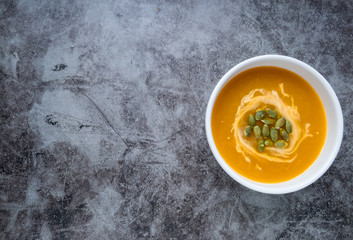 Homemade Pumpkin soup in a bowl with pumpkin seeds, top view, copy space. Seasonal autumn food. vegan food