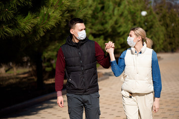 Fototapeta premium Friends in face masks walk in the park for fear of becoming infected with coronavirus.