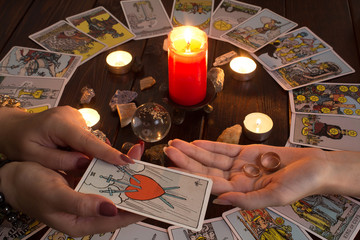 Bangkok,Thailand,March.15.20.The girl holds wedding rings on her hand with Tarot cards,crystals,a magic ball and a lighted candle.Fortune telling for love, the rite of love spell