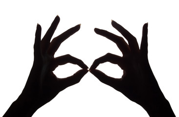 Mask of hands and shadows. Symbol of masquerade and carnival. The okay symbol with his hands. Dark hands on a white background. Light and shadow game. Silhouettes made by hands.