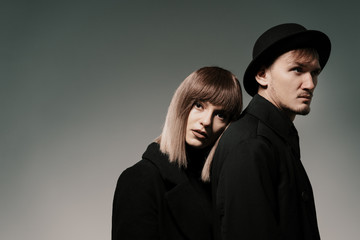 Portrait of urban fashion beautiful couple in black clothes posing over gray background together. Close up fashion portrait of stylish young couple pretty woman and handsome man