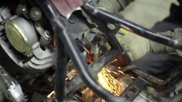 mechanic use angle grinder machine on motorcycle metal frame