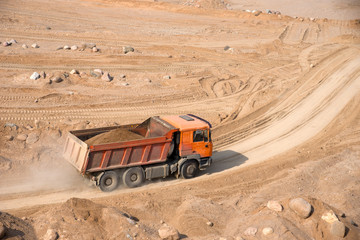 Orange dump truck transports sand in an open pit mine. In the production of reinforced concrete products, concrete for the construction of buildings using coarse sand. Mining industry