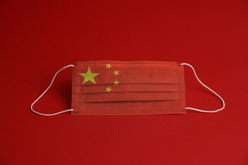 Coronavirus protective mask. Medical mask combined with the China flag. Red background. Face mask protection against pollution, virus, flu. Healthcare and surgery concept.