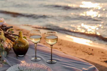 two glasses of champagne and a red rose on the beach