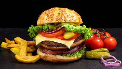 Big burger with french fries on dark background