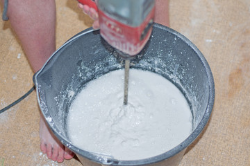 Fototapeta premium A man stirs a mixture for plastering walls in a black bucket