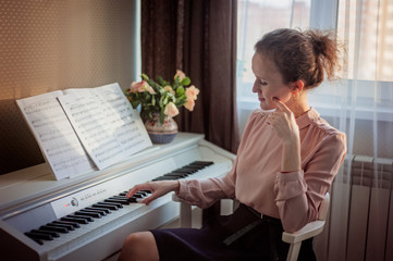 Young beautiful woman is playing piano at home. Music concept