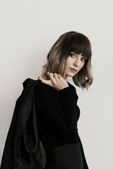 Portrait beautiful woman with attitude wearing black clothes posing on white background looking at camera holding jaket with one finger