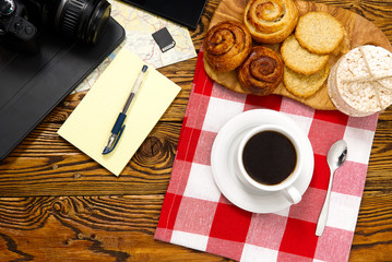 light breakfast, fresh pastries and coffee, on an old wooden table. tourist concept. Travel blogger breakfast building a route plan with cup of coffee