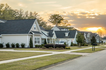 A street view of a new construction neighborhood with larger landscaped homes and houses with yards...