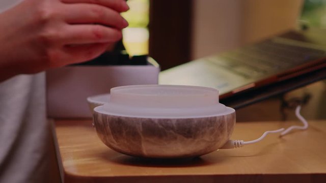 Woman adds essential oil into diffuser