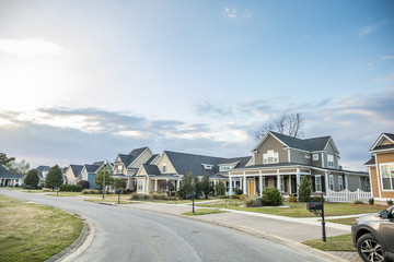 A street view of a new construction neighborhood with larger landscaped homes and houses with yards...