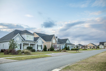 A street view of a new construction neighborhood with larger landscaped homes and houses with yards and sidewalks taken near sunset with copy space © Ursula Page