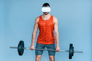 sportsman in virtual reality headset exercising with barbell isolated on blue