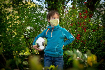 Child with face mask is playing with a ball